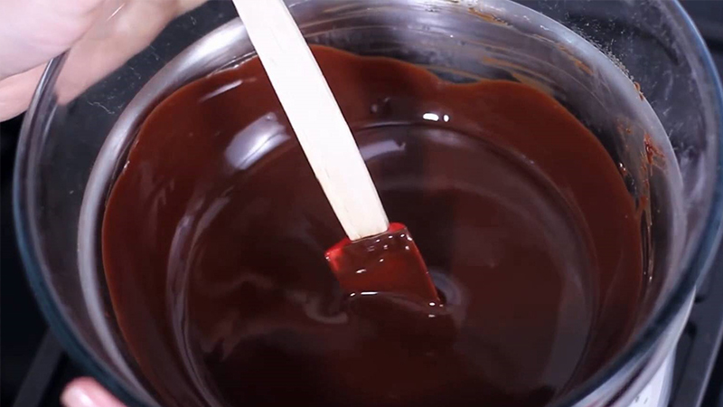Bẻ thanh kẹo socola đã chuẩn bị thành từng miếng nhỏ rồi cho vào nồi đun chảy